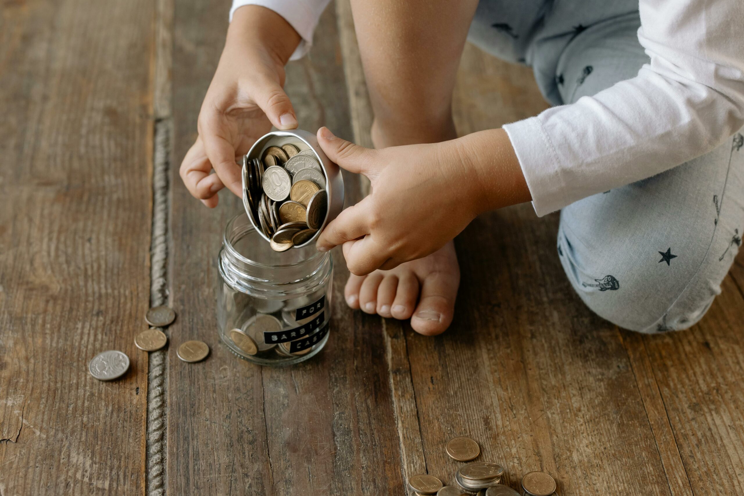 a young child pours coins out from a glass jar
